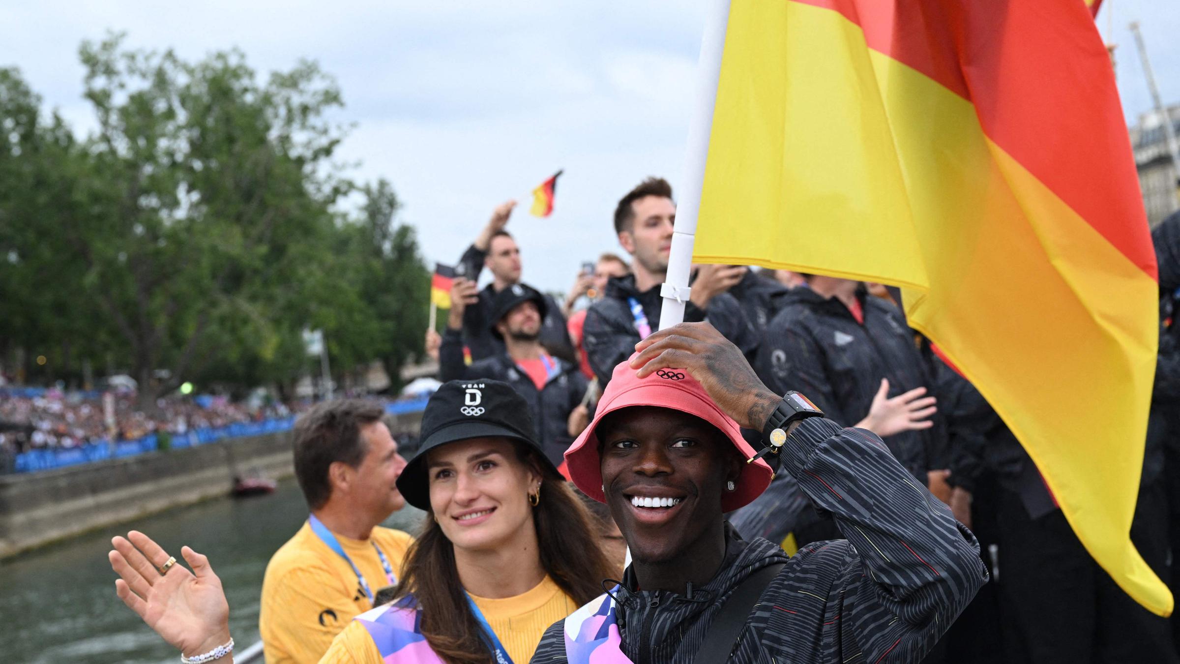 Die Fahnenträger Dennis Schroeder und Anna-Maria Wagner aus Deutschland an Bord eines Bootes bei der schwimmenden Parade auf der Seine während der Eröffnungszeremonie