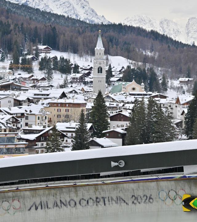 Bob, im Cortina Sliding Centre mit dem Schriftzug "Milano Cortina 2026". Im Hintergrund die Stadt Cortina.