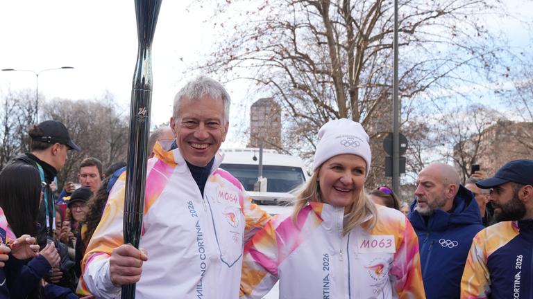 Olympia, Olympische Winterspiele Mailand Cortina 2026, IOC-Präsidentin Kirsty Coventry (r) und James Quincey, CEO von Coca-Cola, stehen bei der Übergabe der olympischen Fackel nebeneinander.