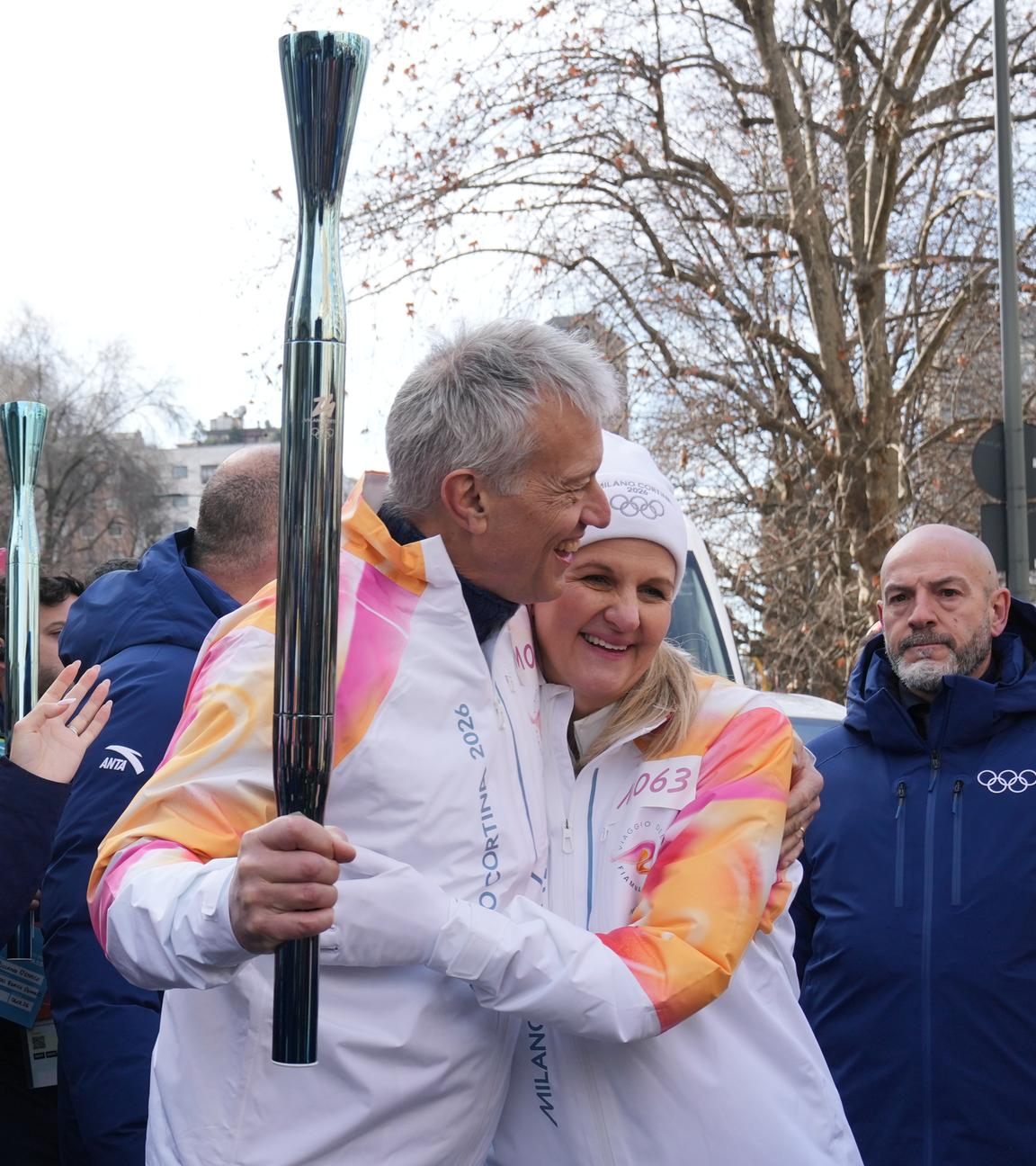 IOC-Präsidentin Kirsty Coventry und James Quincey, CEO von Coca-Cola, umarmen sich bei der Übergabe der olympischen Fackel bei den Olympischen Winterspielen 2026 in Mailand.