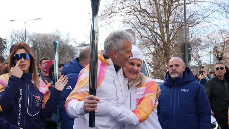IOC-Präsidentin Kirsty Coventry und James Quincey, CEO von Coca-Cola, umarmen sich bei der Übergabe der olympischen Fackel bei den Olympischen Winterspielen 2026 in Mailand.
