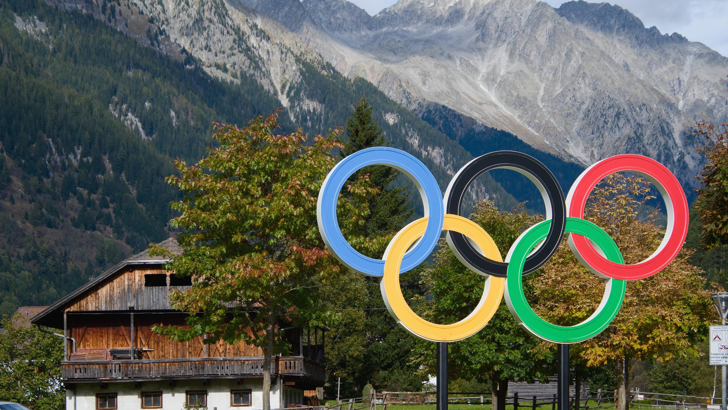 Olympia-Ringe in Cortina vor einem Haus in den Bergen.