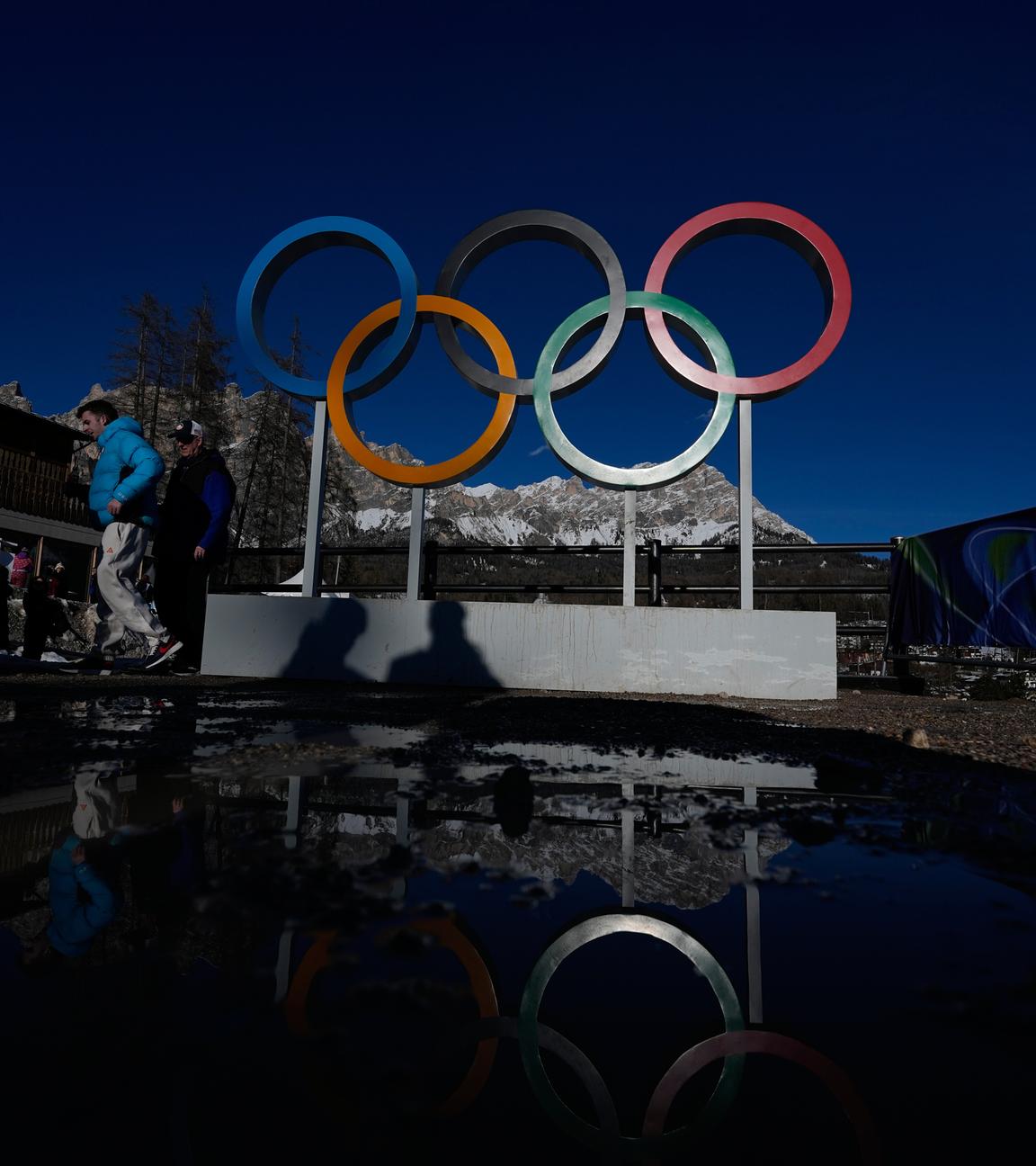 Menschen gehen an den Olympischen Ringen am Sliding Centre bei den Winterspielen 2026 in Cortina d’Ampezzo, Italien, vorbei.