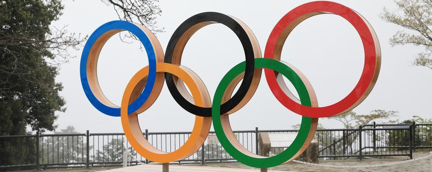Die Olympischen Ringe in fünf verschiedenen Farben auf einem Holzpodest