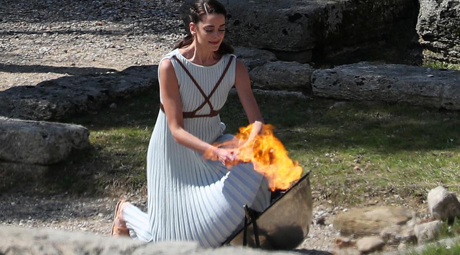 Das Olympische Feuer wird von einer Frau in Toga entzündet