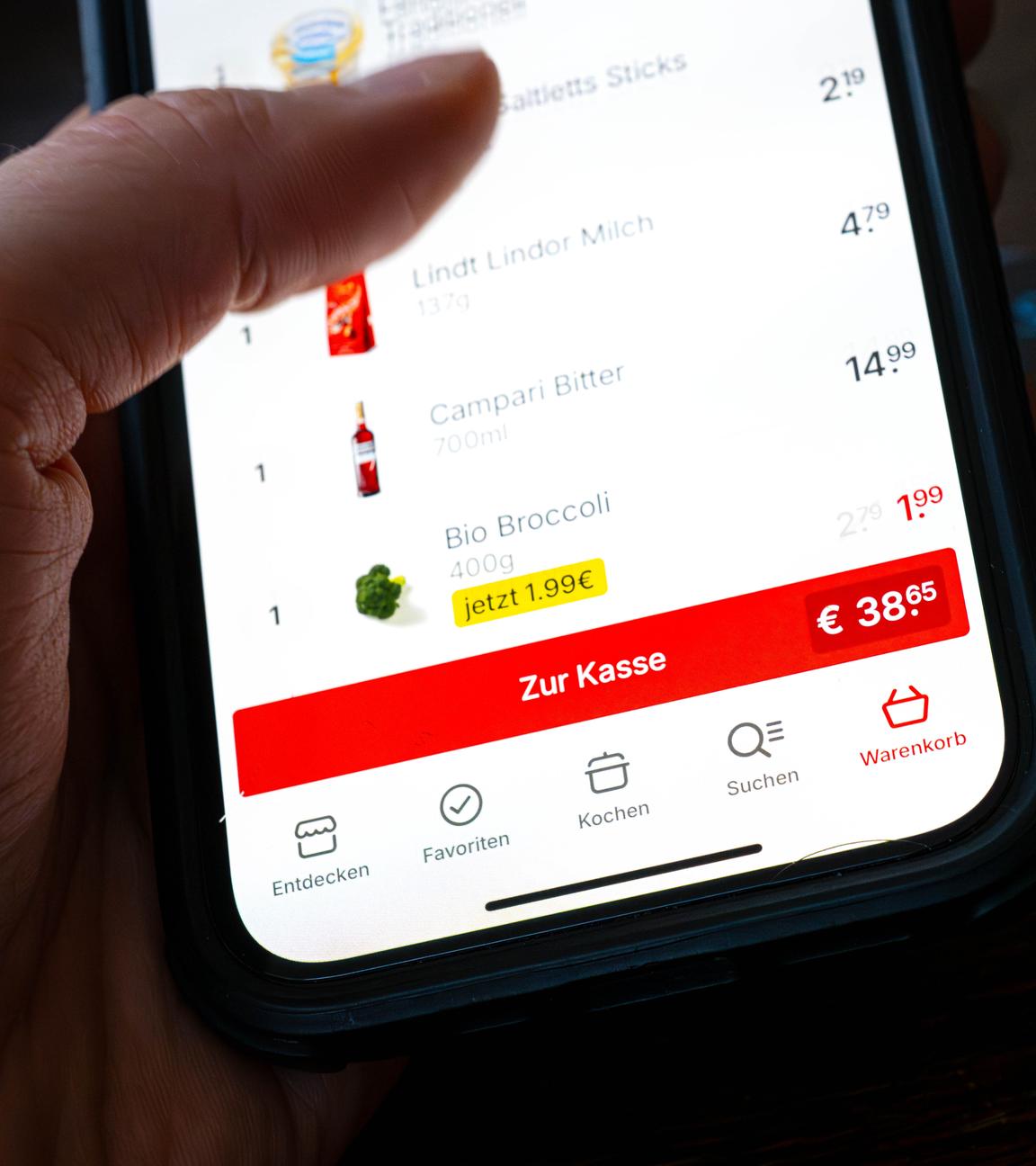 Eine Kreditkarte liegt neben einem Smartphone, auf dem eine App für den Einkauf von Lebensmitteln geöffnet ist.