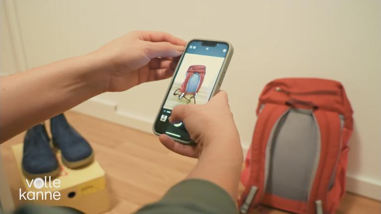 Mit einem Handy werden Fotos von einem Rucksack gemacht.