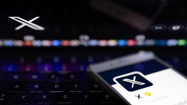  Auf dem offiziellen Profil der Plattform X auf dem Bildschirm eines Smartphones und auf dem Display eines Laptops ist der weiße Buchstabe X auf schwarzem Hintergrund zu sehen. 