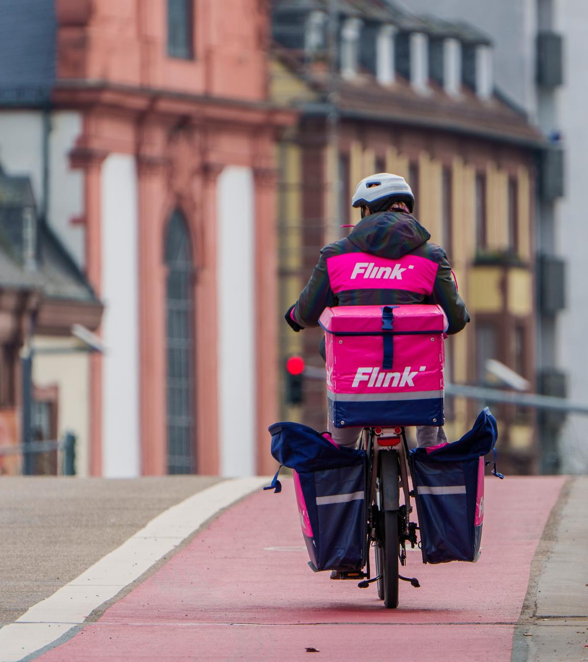 Ein Mitarbeiter des Lieferdienstes "Flink" radelt am 22.03.2024 über die Alte Brücke in Frankfurt am Main.