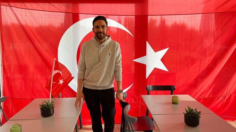 Onur Tuac, Vorstandsmitglied beim Verein Anadolu Türkspor, steht im Vereinsheim vor einer türkischen Fahne.