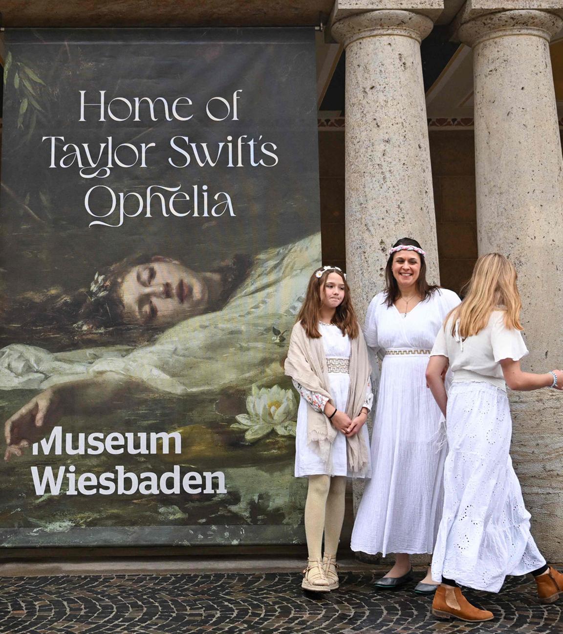 Fans der US-Sängerin Taylor Swift posieren vor dem Plakat "Home of Taylor Swift’s Ophelia“ vor dem Museum in Wiesbaden.