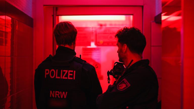 Zwei Polizisten (von hinten zu sehen) bei einem Einsatz