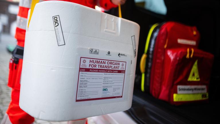 Ein Mitarbeiter des DRK stellt eine Kühlbox für eine Organspende in einen Transporter des Deutschen Roten Kreuzes. 