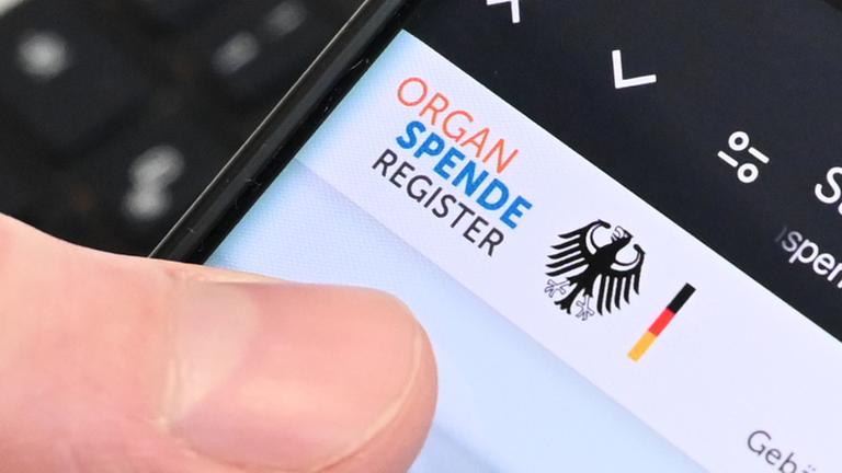 Berlin: Eine Person hält ein Handy in der Hand, auf dem das Online-Portal zur Registrierung zur Organspende zu sehen ist.