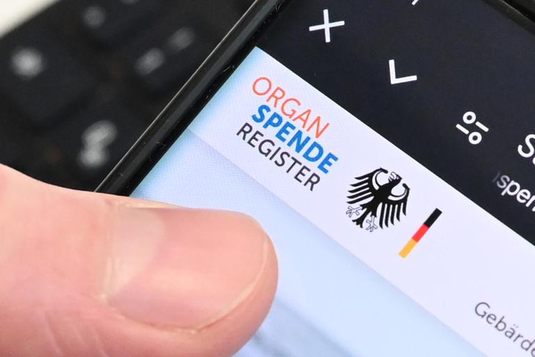 Berlin: Eine Person hält ein Handy in der Hand, auf dem das Online-Portal zur Registrierung zur Organspende zu sehen ist.