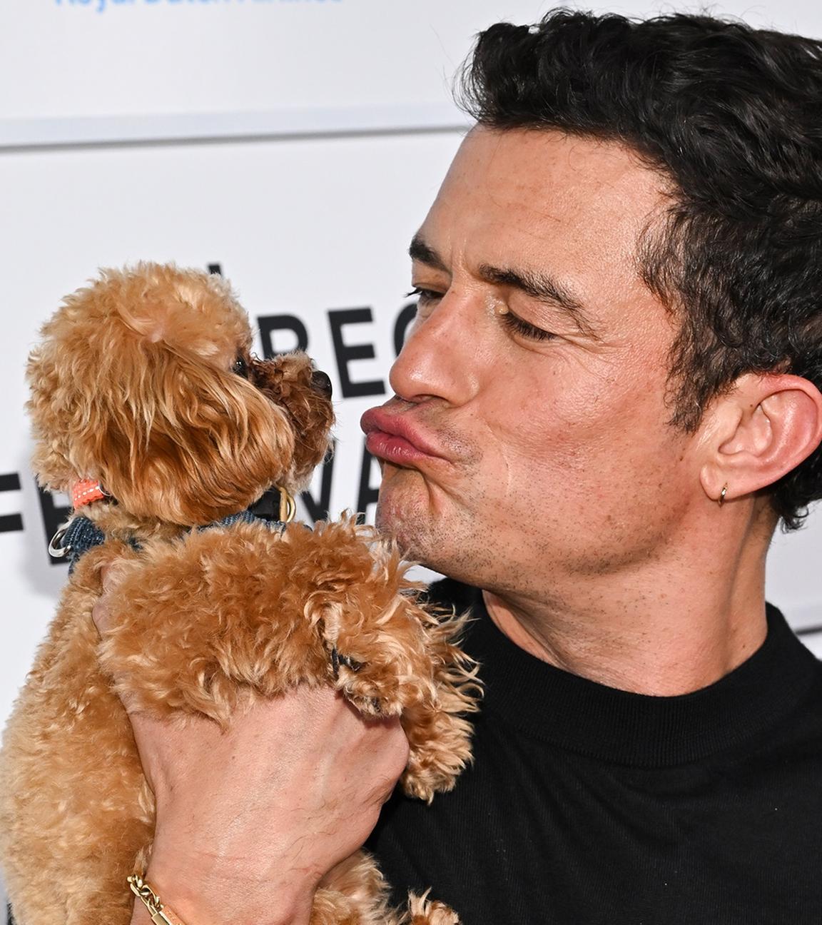 Orlando Bloom macht einen Kussmund zu seinem Hund auf dem Arm