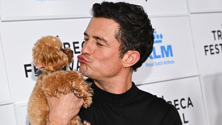 Orlando Bloom macht einen Kussmund zu seinem Hund auf dem Arm