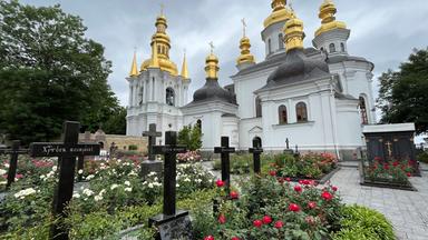 Ukraine, Kiew: Auf dem Gelände des Höhlenklosters stehen Kirchengebäude und auf einem Friedhof mit Gräbern Kreuze.
