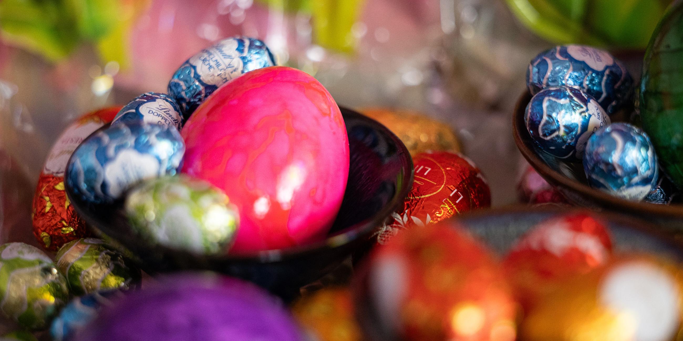 Ostereier und Schokoeier liegen in Schalen und auf einem Tisch.