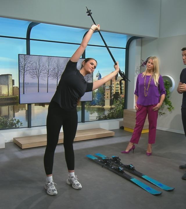 Drei Personen stehen im Studio, eine macht Sportübungen