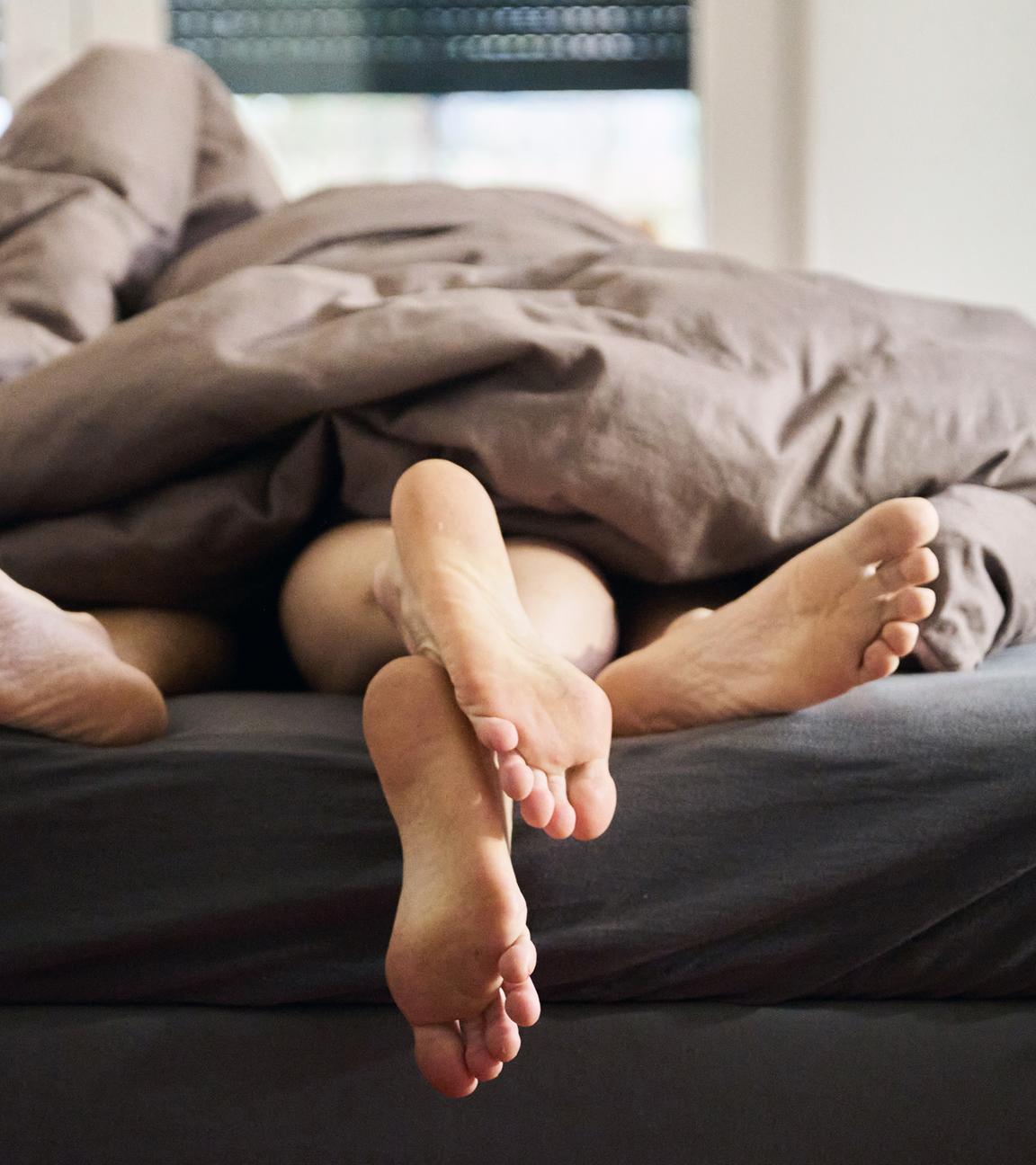 Eine Frau und ein Mann liegen eng umschlungen in einem Bett.