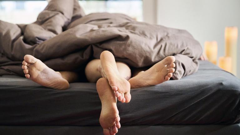 Eine Frau und ein Mann liegen eng umschlungen in einem Bett.