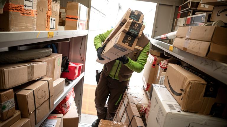 Ein Paketbote von UPS lädt Pakete in einen Transporter.