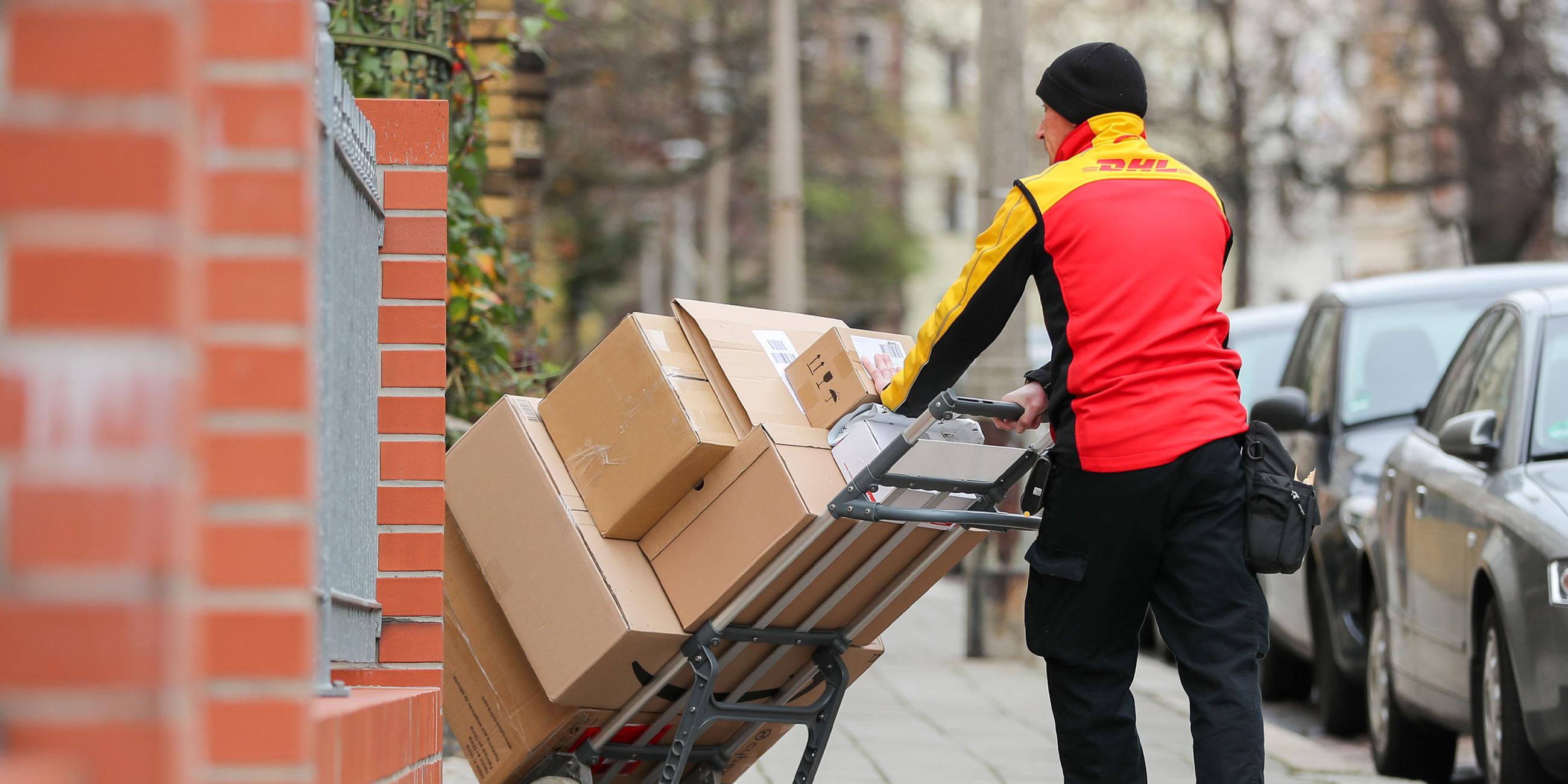Ein Paketzusteller der DHL liefert Pakete aus. (Archiv)