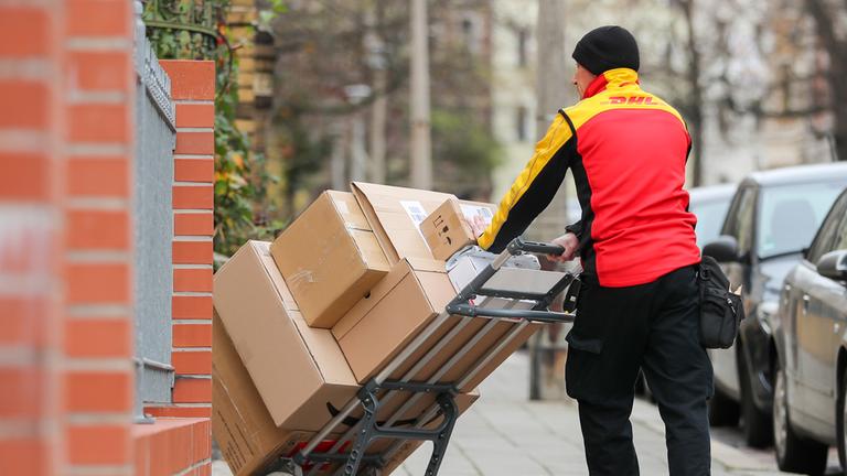 Ein Paketzusteller der DHL liefert Pakete aus. (Archiv)