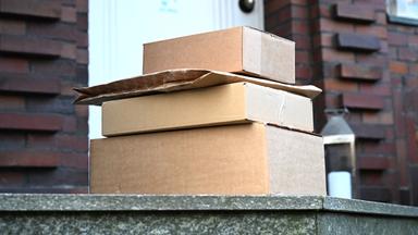 Vier von einem Paketboten gebrachte Pakete liegen vor einer Haustür.