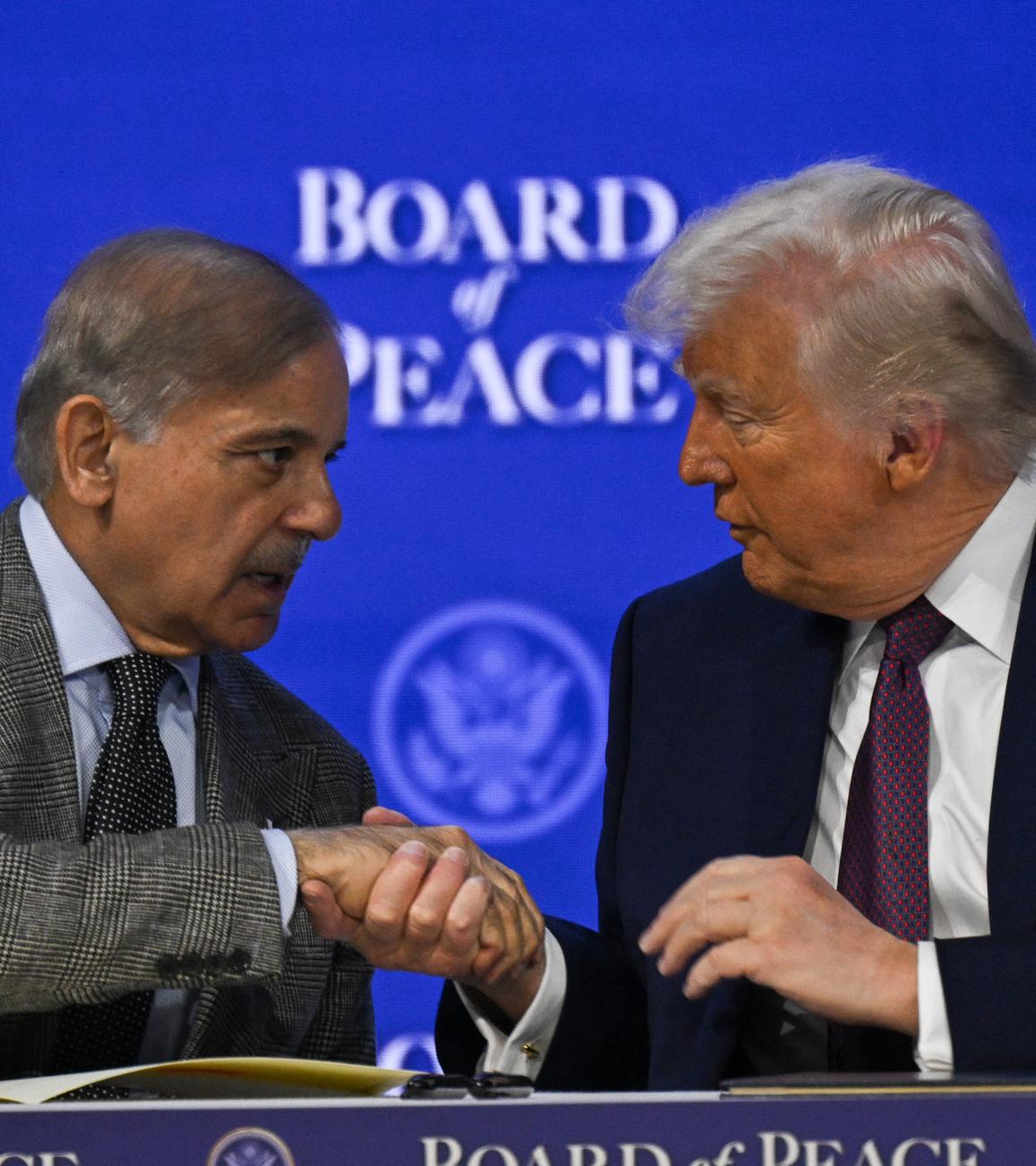 Donald Trump und Shebaz Sharif reichen sich die Hände vor blauem Hintergrund.