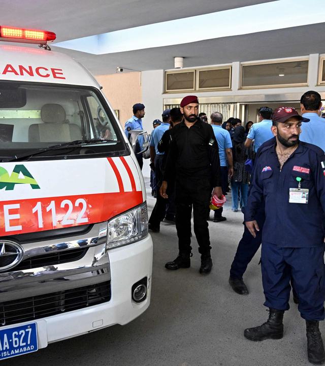 Sicherheitspersonal steht neben einem Krankenwagen nach einem Brand vor der Abteilung für Mutter-Kind-Gesundheit (MCH) des Pakistan Institute of Medical Sciences (PIMS) in Islamabad. 