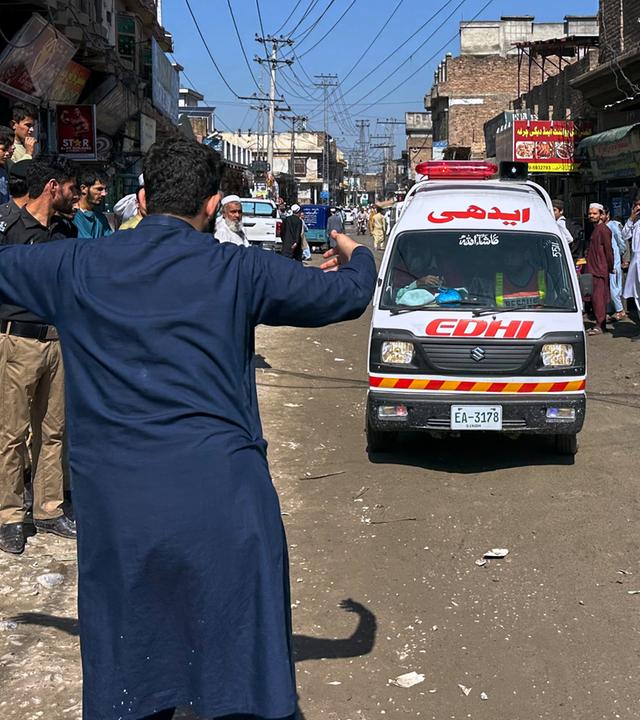 Pakistan, Peschawar: Ein freiwilliger Helfer macht den Weg frei für einen Krankenwagen, der verletzte Schulkinder transportiert