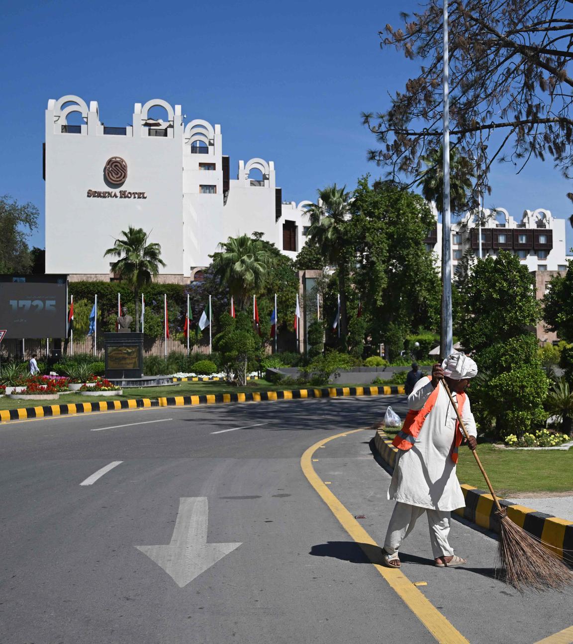 Pakistan, Islamabad: Ein Arbeiter fegt die Straße vor dem Serena Hotel