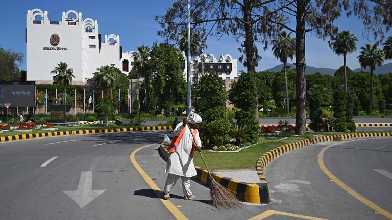 Pakistan, Islamabad: Ein Arbeiter fegt die Straße vor dem Serena Hotel