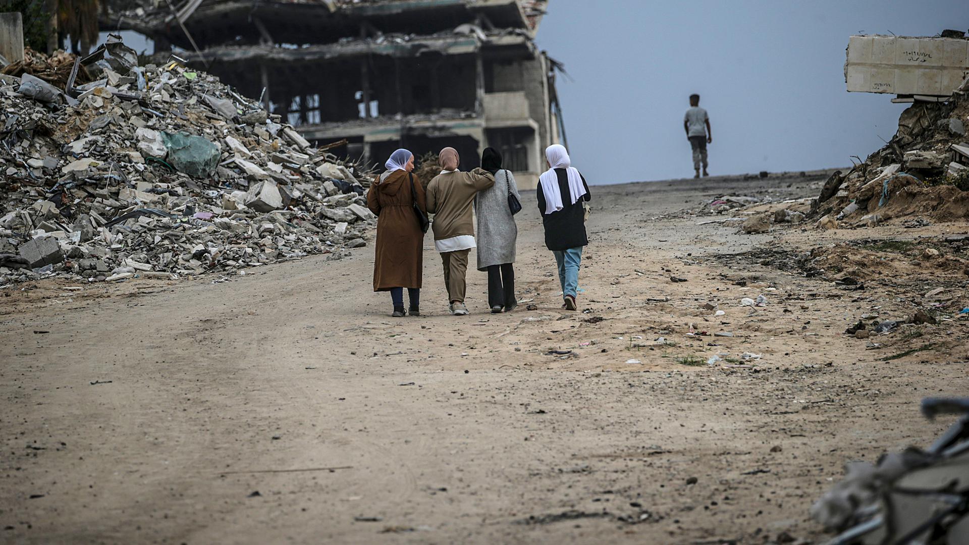 Eine Gruppe intern vertriebener palästinensischer Frauen geht am 1. April 2025 in Gaza-Stadt, Gazastreifen, in der Nähe der Trümmer zerstörter Gebäude eine Straße entlang, nachdem sie auf Befehl der israelischen Armee aus dem Norden des Gazastreifens geflohen waren. 