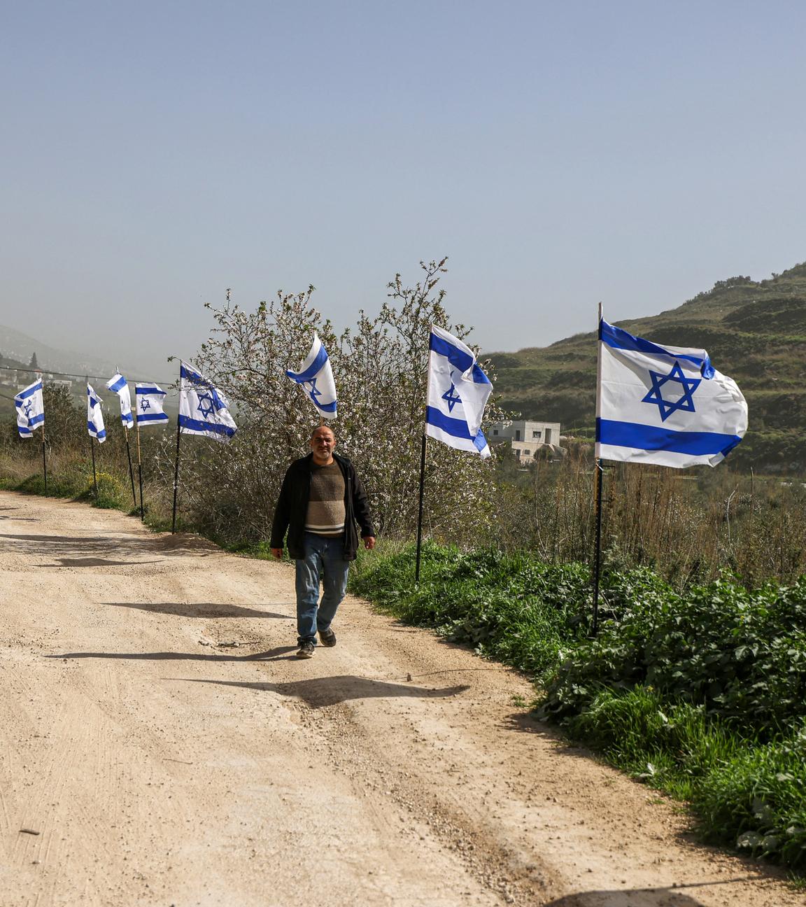 Ein palästinensischer Mann aus dem Dorf Burqa geht an einem Zaun vorbei, der mit israelischen Flaggen dekoriert ist