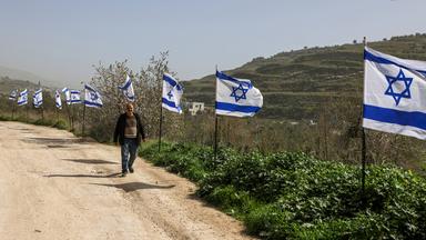 Ein palästinensischer Mann aus dem Dorf Burqa geht an einem Zaun vorbei, der mit israelischen Flaggen dekoriert ist