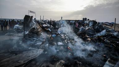 Palästinensische Gebiete, Rafah: Palästinenser inspizieren zerstörte Zelte und Unterkünfte neben einem ausgebrannten Auto nach einem israelischen Luftangriff auf ein Flüchtlingslager.