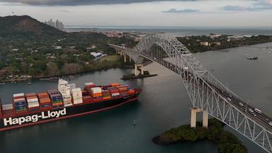Ein Frachtschiff fährt unter der Las Americas-Brücke durch den Panamakanal. 