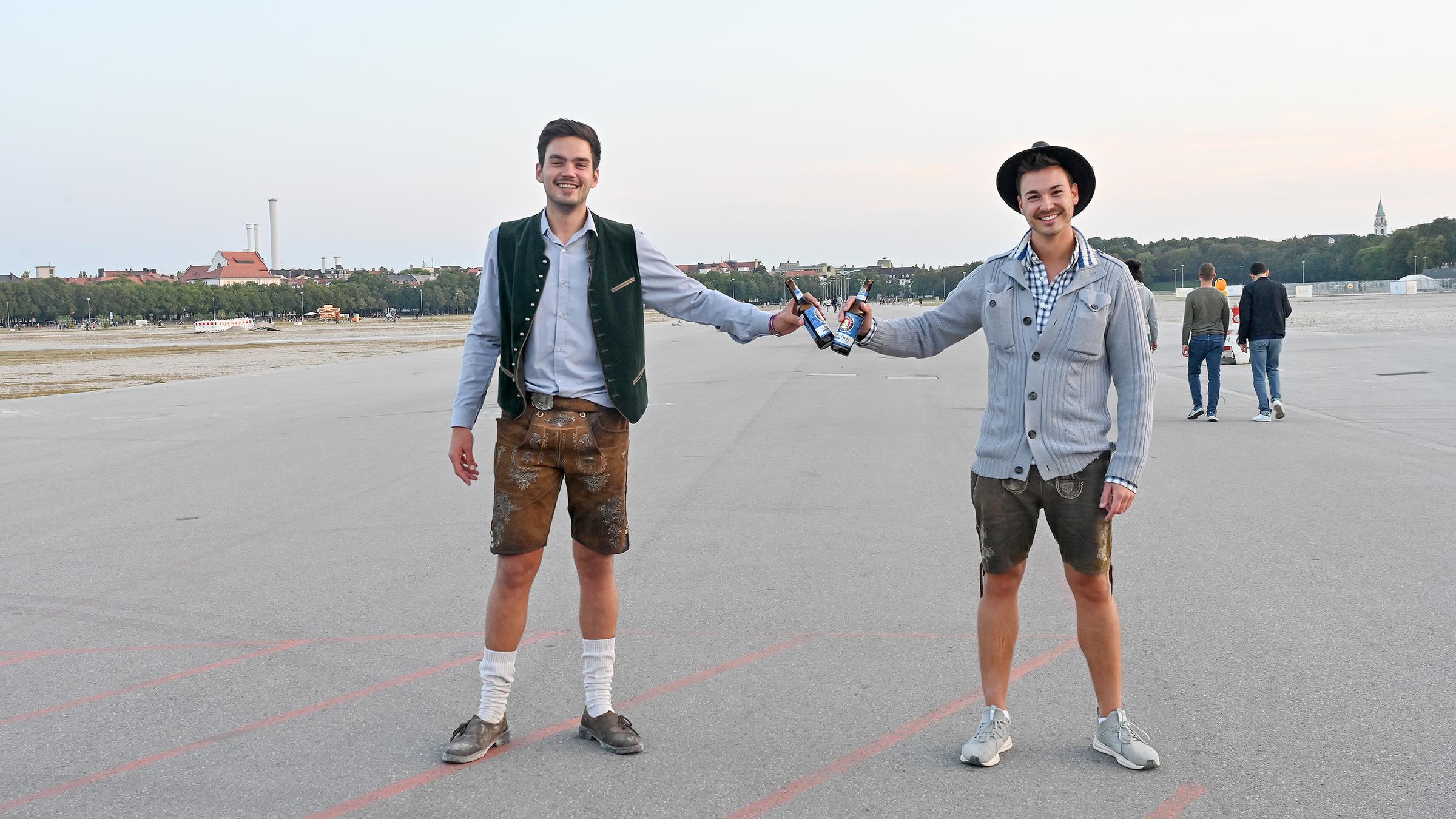 Zwei Männer prosten sich auf der leeren Theresienwiese zu.