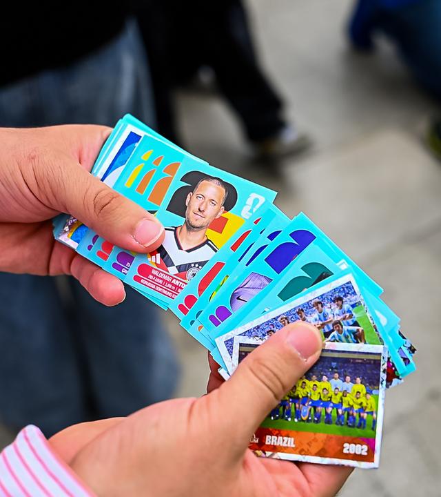 Eine Person hält Panini-Sticker in der Hand. Auf einem Sticker ist Waldemar Anton (Deutschland) zu sehen
