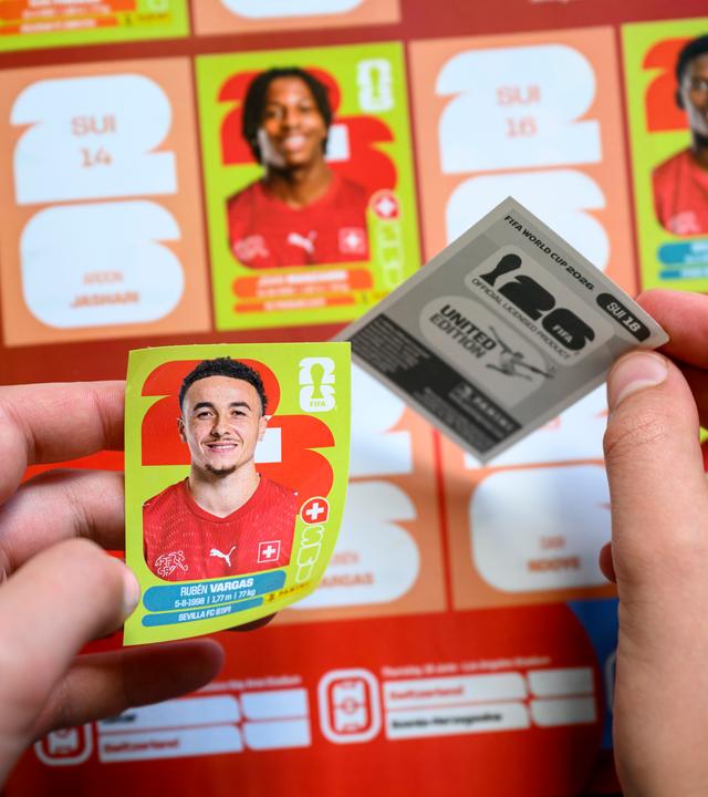 Ein Sticker wird in das offizielle Panini Album der Fußball WM 2026 eingeklebt.