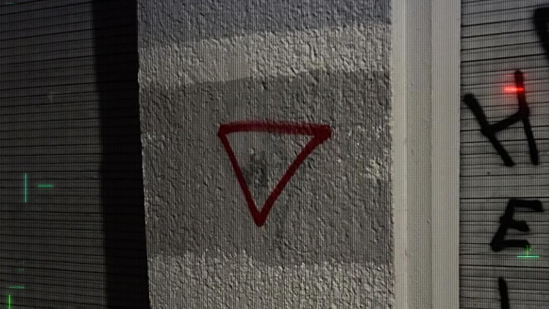 Auf einer weißen Wand wurde ein rotes Dreieck gesprüht.
