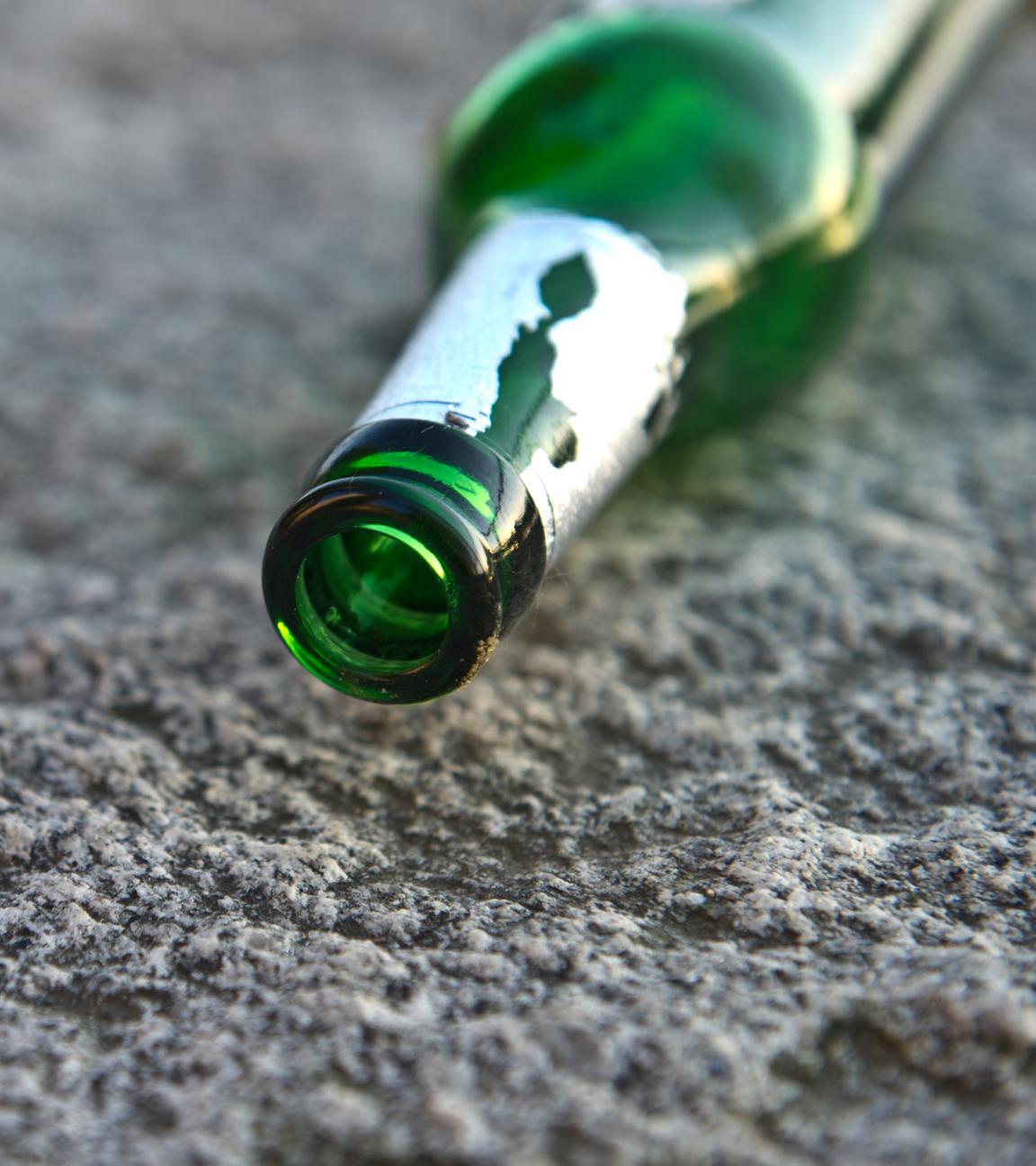 Eine leere Bierflasche liegt auf dem Asphalt.