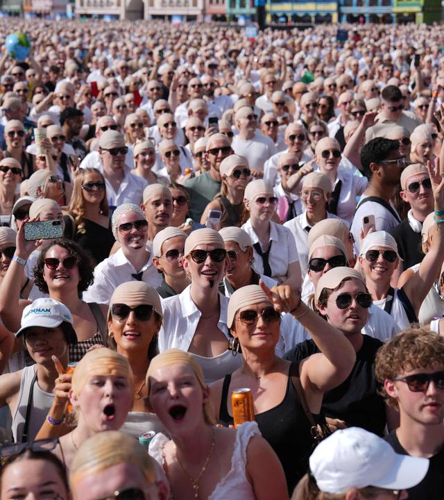 Zuschauer mit Glatzenattrappen versammeln sich am 10. Juli 2026 im Sonnenschein vor einem Konzert des US-Rappers und Sängers Pitbull im Londoner Hyde Park.
