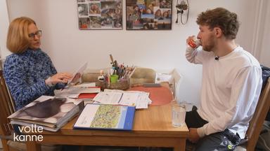 Ein Mann und eine Frau sitzen sich am Tisch gegenüber. Vor ihnen liegen Papierstapel, Ordner und diverse Unterlagen.