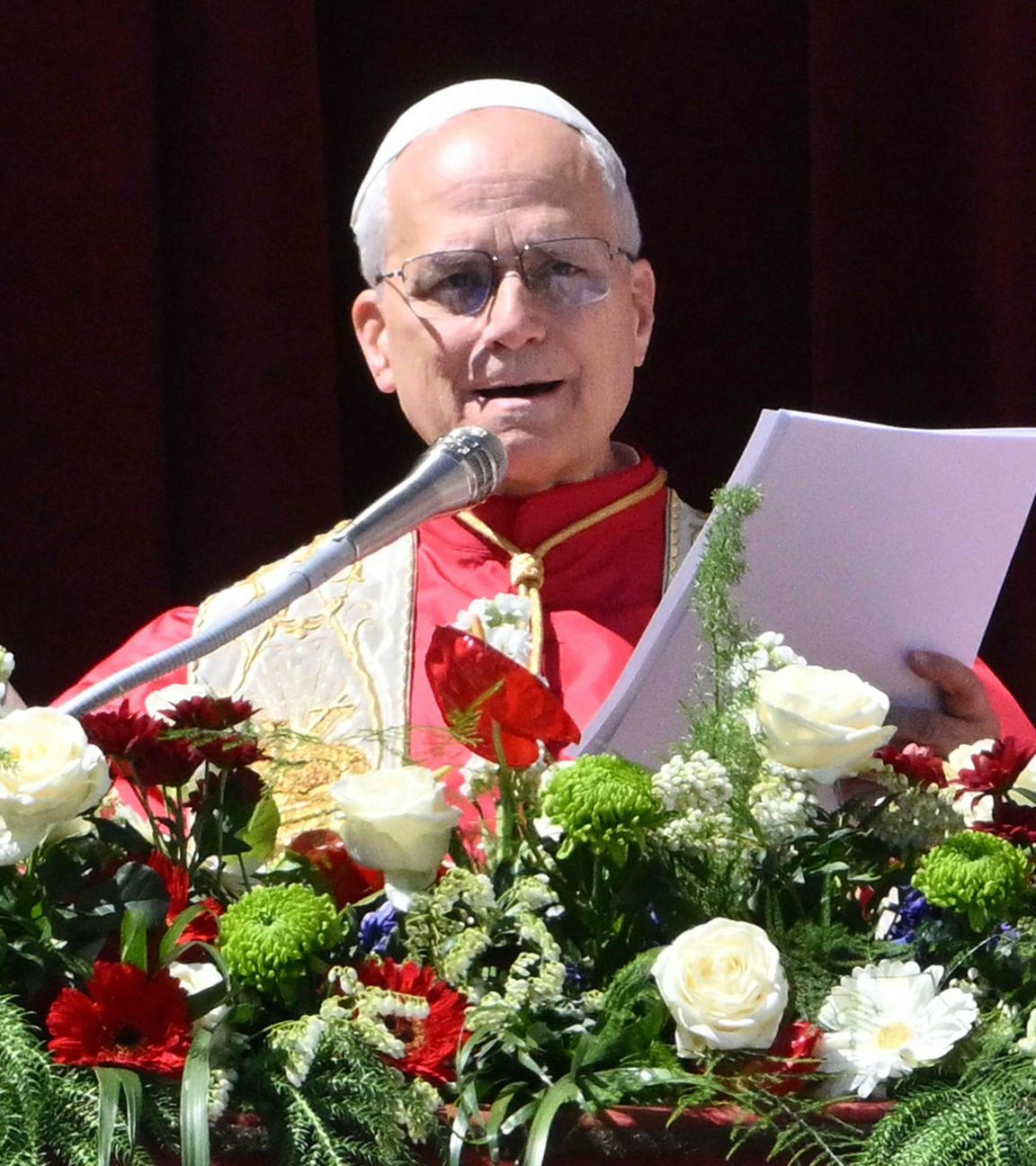 Papst Leo XIV. steht auf dem Hauptbalkon des Petersdoms, vor ihm sind Blumen am Geländer angebracht.