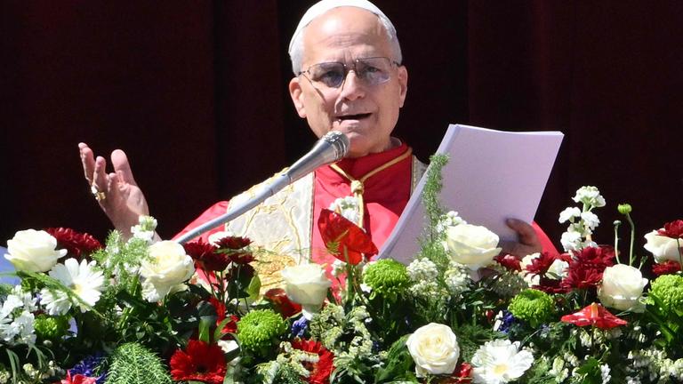 Papst Leo XIV. steht auf dem Hauptbalkon des Petersdoms, vor ihm sind Blumen am Geländer angebracht.