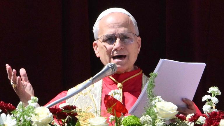 Papst Leo XIV. steht auf dem Hauptbalkon des Petersdoms, vor ihm sind Blumen am Geländer angebracht.